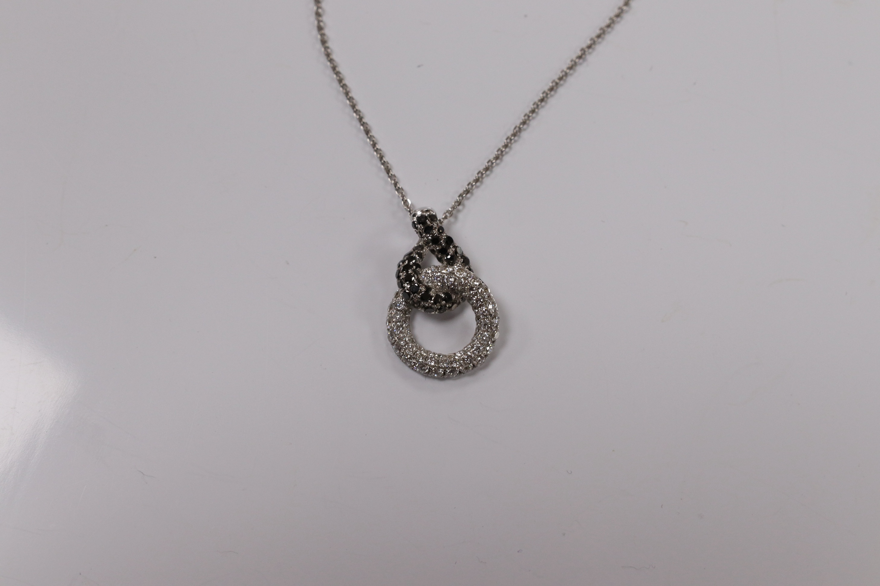 A modern 18k white metal and diamond chip set double loop pendant, 20mm, on an 18k white metal chain, 40cm, gross weight 4.1 grams. Condition - fair